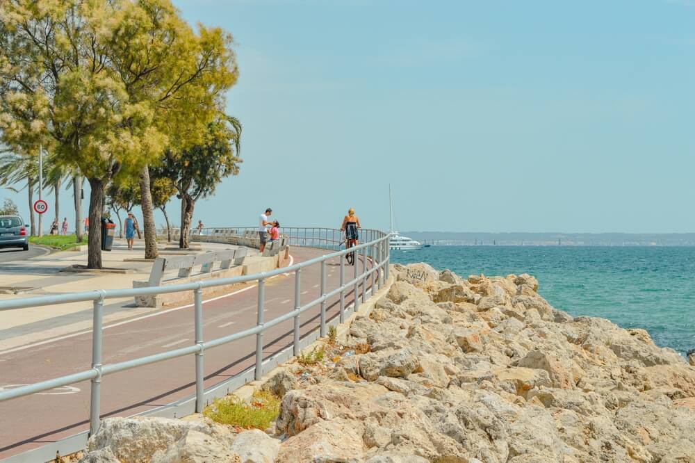 Cycling in Mallorca: A woman on a bike, cycling along a bike path next to the sea