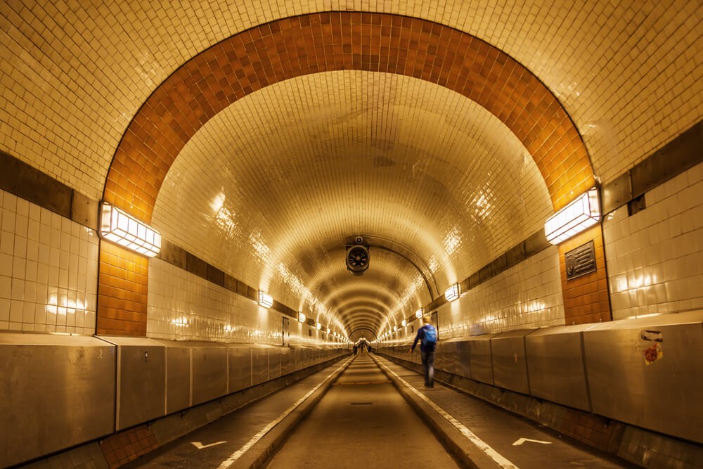 Things to do in Hamburg: Cream tiled tunnel with a road, pavements and a person walking