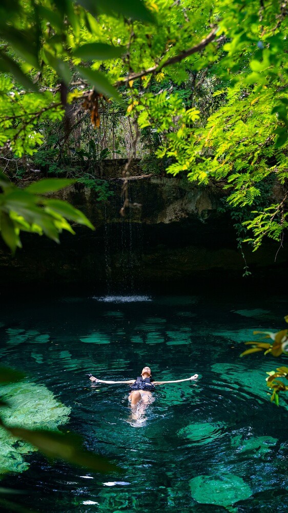 Girls’ Trip Ideas: Woman bathing in a natural cenote pool surrounded by plants