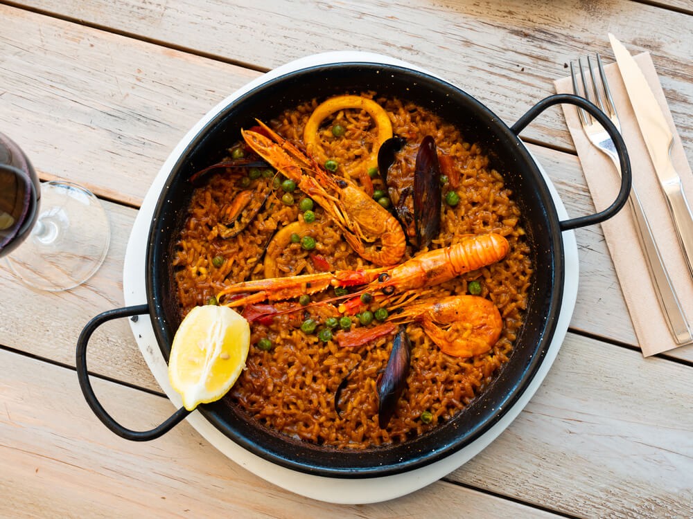 Origins of paella: A paella pan full of seafood paella and with a lemon on top