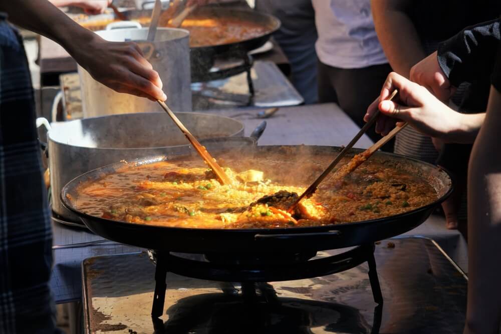 Paella pan: Three men cooking a large paella in a traditional paella pan