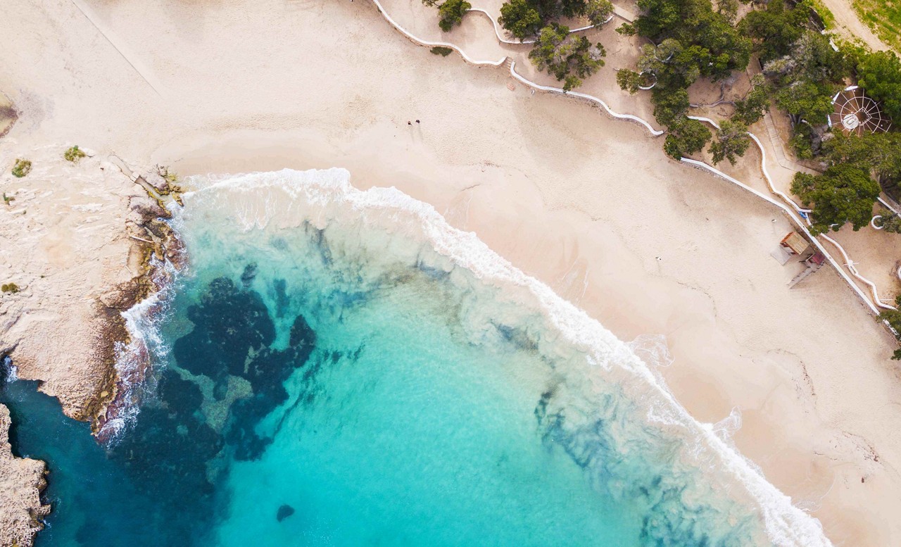 Best beaches in Ibiza: A bird’s eye view of white sand and topaz waters of the beach