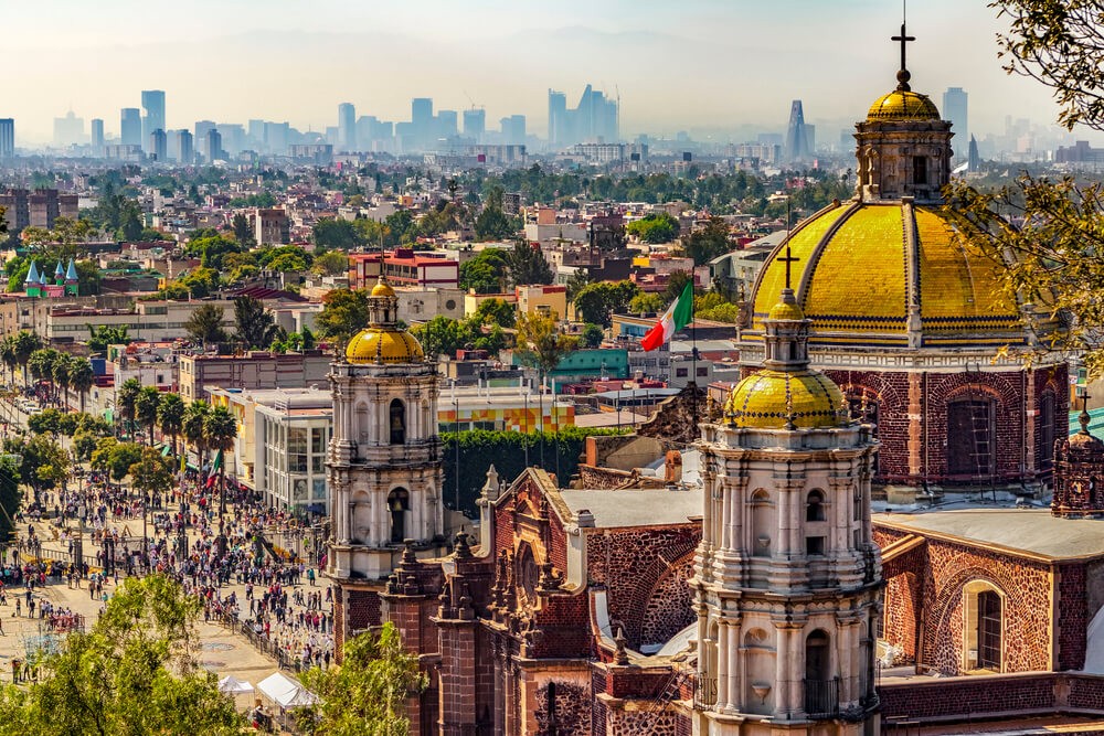 Basílica de Nuestra Señora de Guadalupe with a crowd in front and skyscrapers on the horizon. 