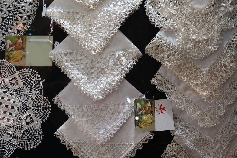 Maltese Lace: Lace fabrics hanging on a market stand wall