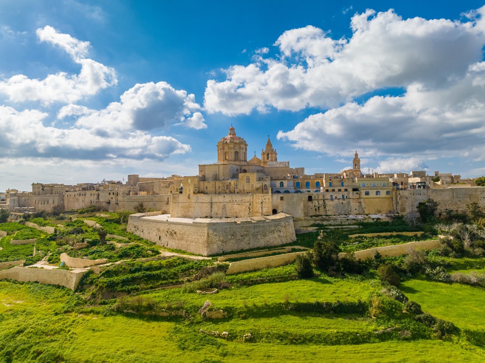 Mdina: An emblematic building on a hill surrounded by green landscape