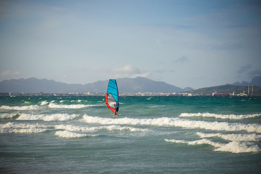 Windsurfing in Mallorca: Man windsurfing on a Mallorca beach with the island in the background