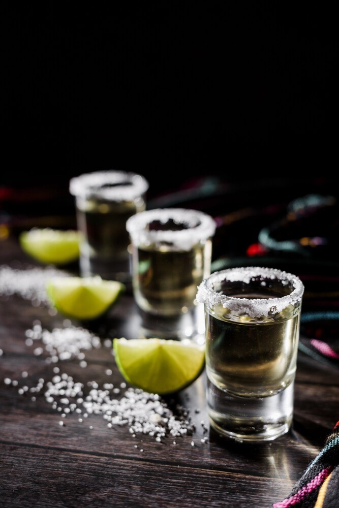 Shots of tequila: Three tequila shot glasses in a row with salt and lime