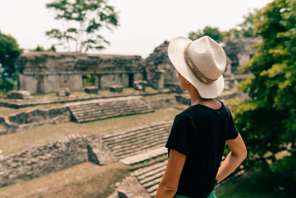 A woman wearing a hat while exploring Mayan ruins.