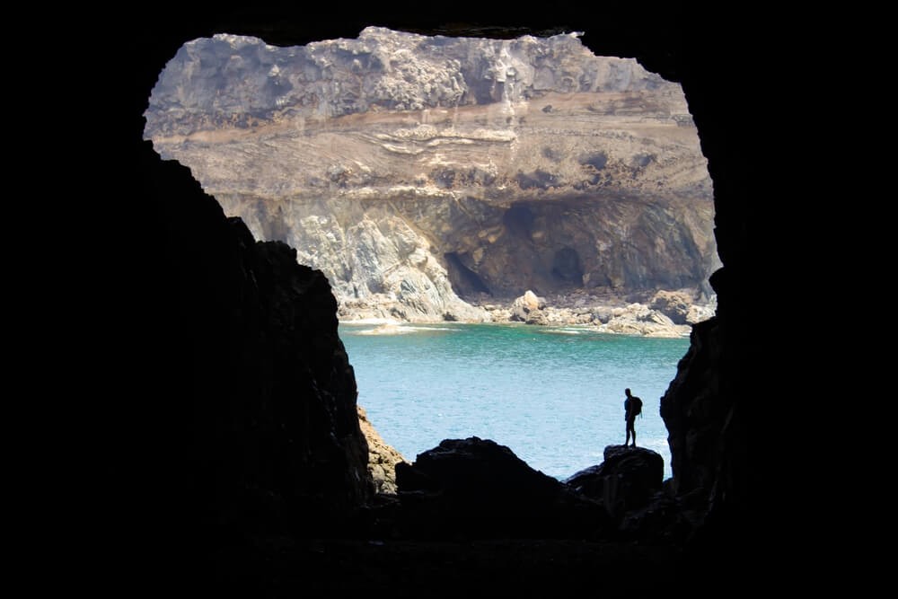 Fuerteventura family holidays: A man standing inside an opening of the Ajuy caves