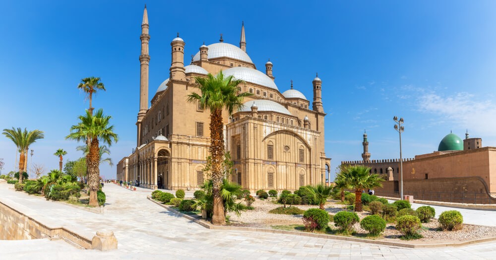 Muhammed Ali Mosque: A sandstone mosque in a plaza with turrets, domes and palms