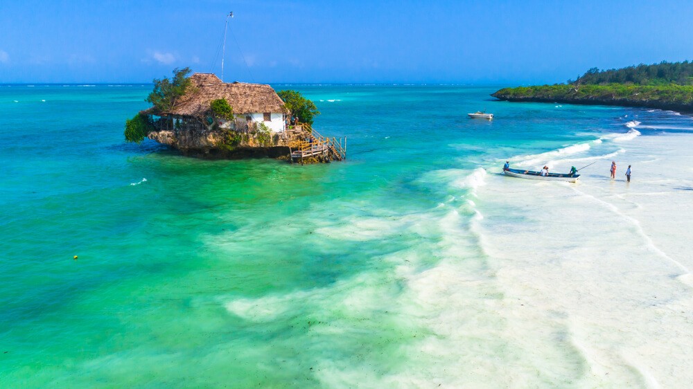 White sand and topaz sea with a rock in the middle and a house on top